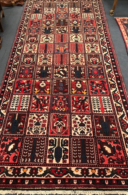 A Baktiari brick red ground rug 360 x 152cm